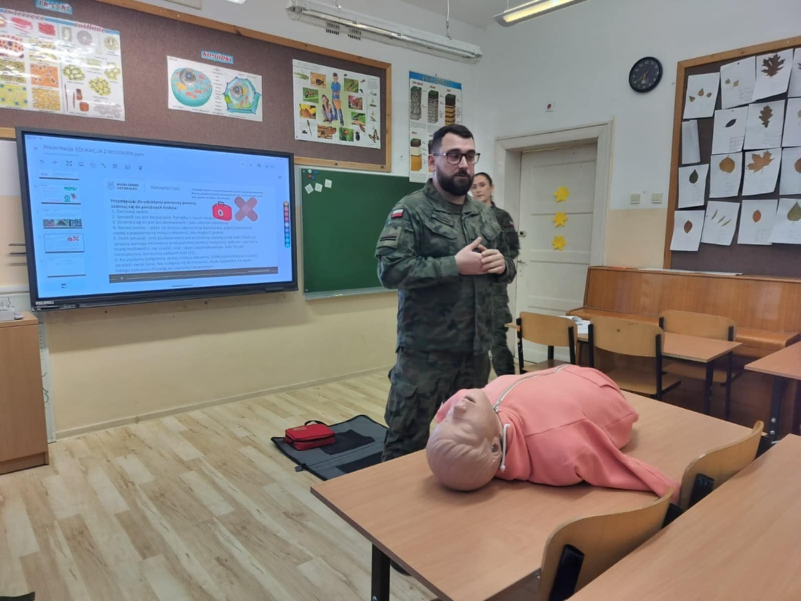 Żołnierz uczy pierwszej pomocy uczniów w klasie. 