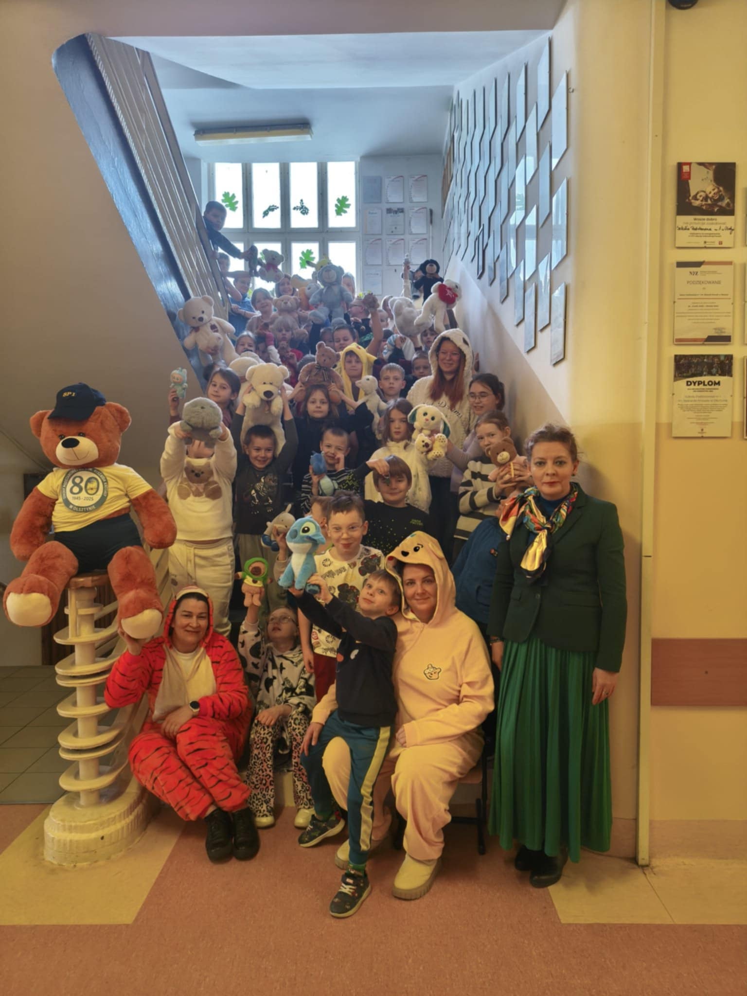 Dzieci i nauczyciele przebrani za pluszaki i trzymający swoje maskotki.